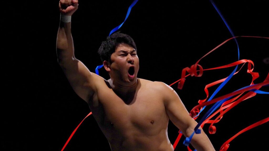 Man shirtless, shouting with fist raised, blue and red ribbons swirling around him in darkness, celebrating victory