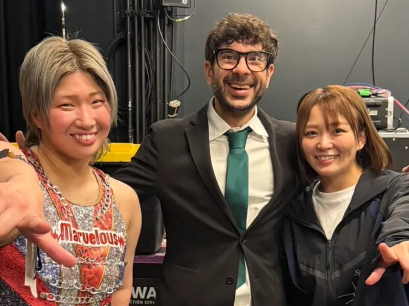 Three people pose for a backstage selfie, smiling with arms around each other and stage equipment in the background.