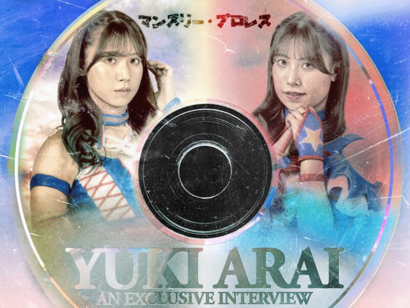 Two women in blue outfits pose inside a large vinyl record design, with the caption 'An Exclusive Interview' visible.