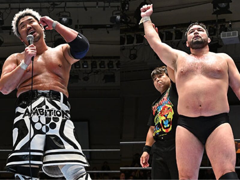 Two professional wrestlers stand in the ring: one with a microphone and patterned black-and-white trunks, the other raising a fist as a referee looks on from behind.