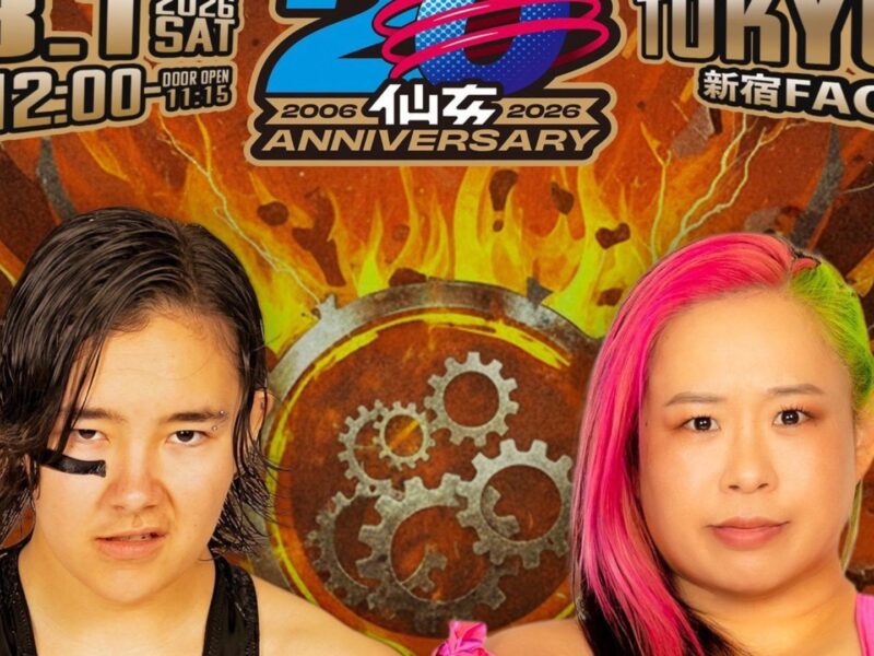 Two people with bold makeup and colorful hair stand in front of a fiery wrench-and-gear poster celebrating a 20th anniversary.